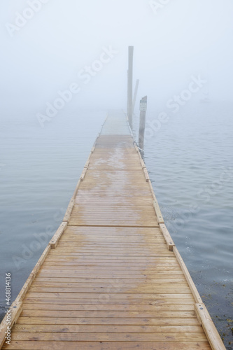 A long wooden dock sits on the bay shrouded in thick fog.