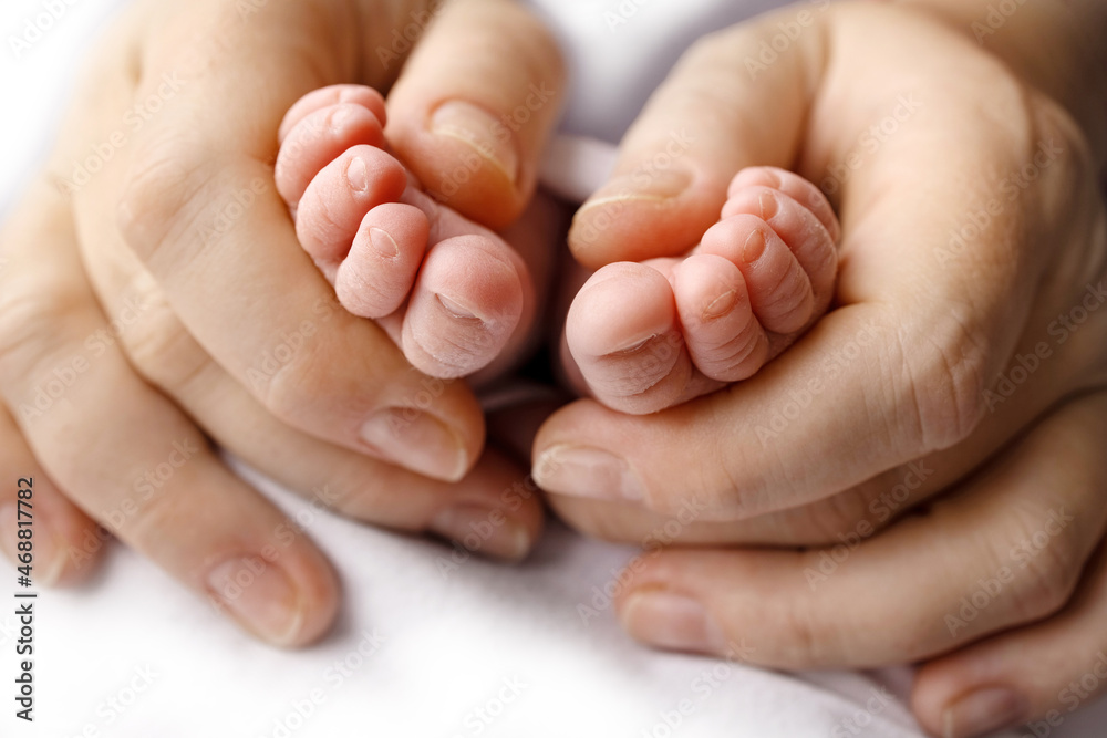 Legs, toes, feet and heels of a newborn. With the hands of parents, father, mother gently holds the child's legs. Macro photography, close-up. Legs, toes, feet and heels of a newborn. With the hands of parents, father, mother gently holds the child's legs. Macro photography, close-up.