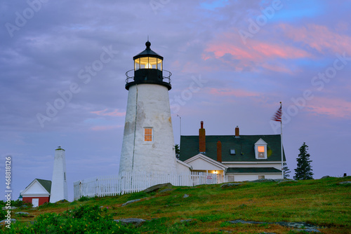 Pink dawn light on the beautiful Pemaquid Lighthouse with the orange sunrise reflected in the lighthouse windows