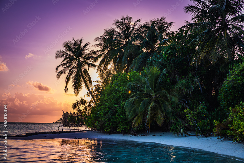 Sunset on a paradise island with turquoise water and exotic vegetation - the Maldives