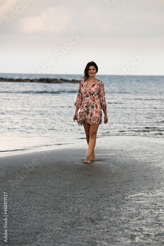 Young woman walking barefoor on a sandy beach.