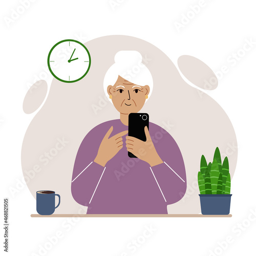 Grandmother holds a mobile phone in her hand. Elderly woman learning to use the telephone.