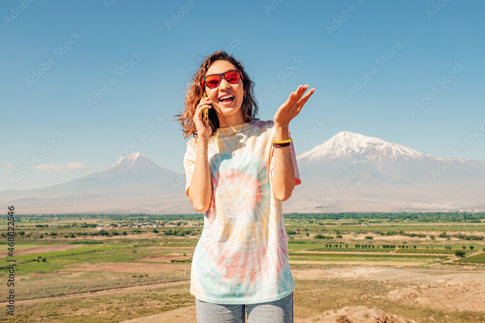 Woman is talking on a mobile phone against the background of the famous Mount Ararat. The concept of telecom operators in Armenia