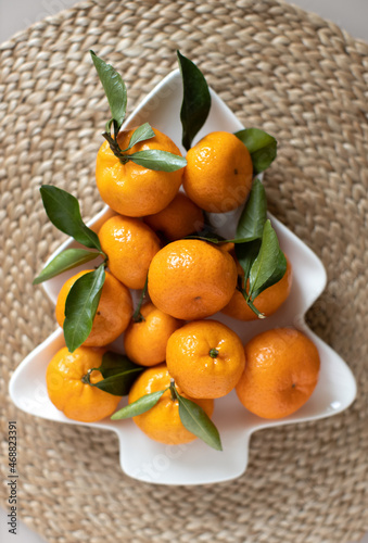 Wallpaper Mural Small ripe tangerines with leaves, on plate in shape of Christmas tree on wicker serving napkin. Concept winter vitamin food. Moody still life festive composition. For greeting card, book, stories Torontodigital.ca