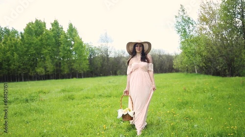 Woman in summer hat and retro dress walking happy in field in a summer day