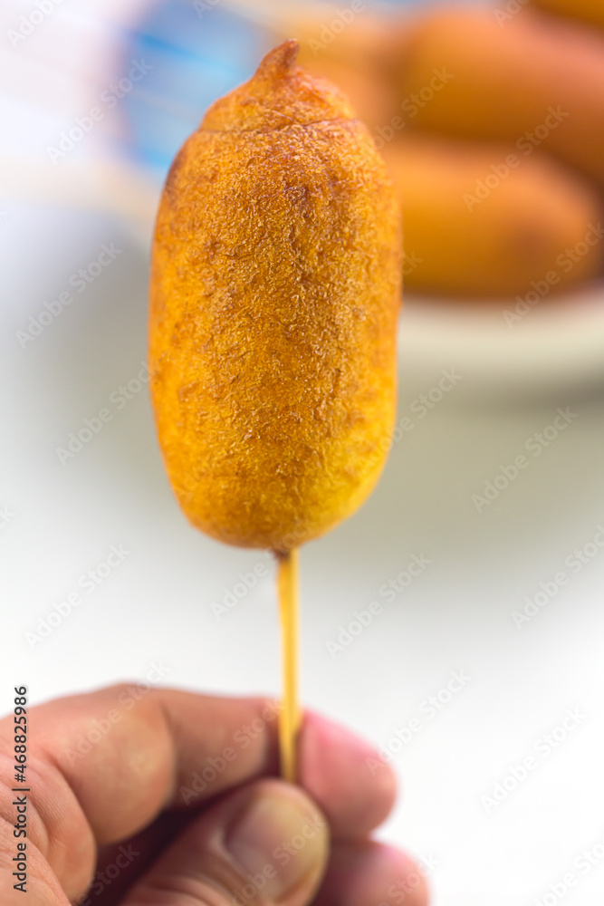 Man holds Corn dogs cooked with sausage and dough - obrazy, fototapety, plakaty 
