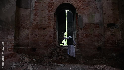 A creepy old woman witch or sorceress wanders through a ruined church