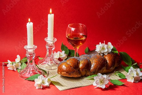 Challah bread, shabbat wine and candles on red background. Lighting a candle. Shabbat Shalom