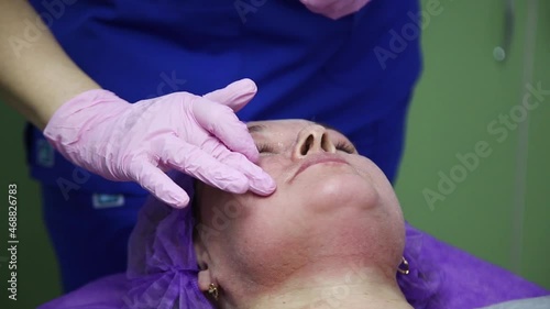 A woman lies on a couch in the office of a dermatologist and receives a cosmetic procedure. CO2 grinding