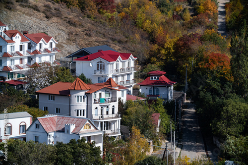 Bright autumn landscape. A snow-white hotel with red roofs among the hills.
