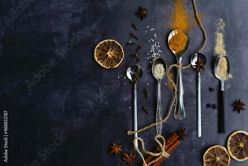 Fragrant autumn spices for baking on spoons on a dark background. Copy space. View from above.