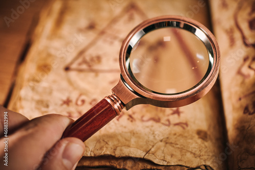 Magnifying glass and the ancient magic book on wooden table photo