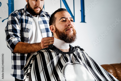 Hairdresser placing wrapping paper around the client neck.
