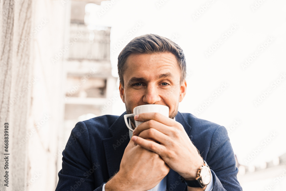 Man like coffee. Handsome man with cup of coffee in cafe. Morning lifestyle of male. Man is sitting on the summer terrace in cafe, drinking coffee and smiling. Man like coffee. Handsome man with cup of coffee in cafe. Morning lifestyle of male. Man is sitting on the summer terrace in cafe, drinking coffee and smiling.