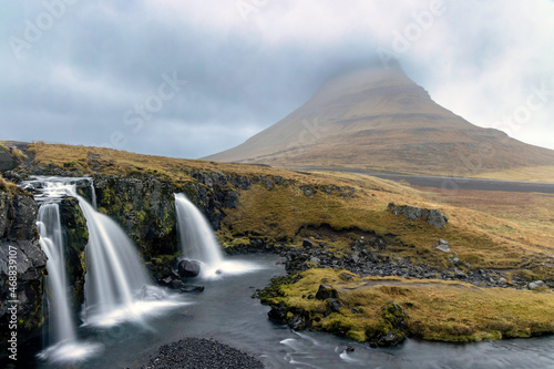 Kirkjufellsfoss waterfall and Kirkjufell Mountain on the Snaefellsnes Peninsula in Iceland on a foggy morning.