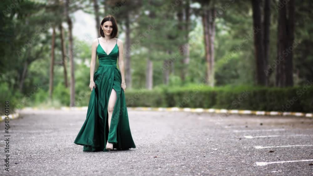 Beautiful smiling young woman in a long luxury silk satin green dress ...