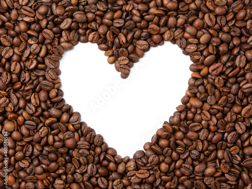 Texture of roasted coffee beans on white isolated background. In the center is the shape of the heart.