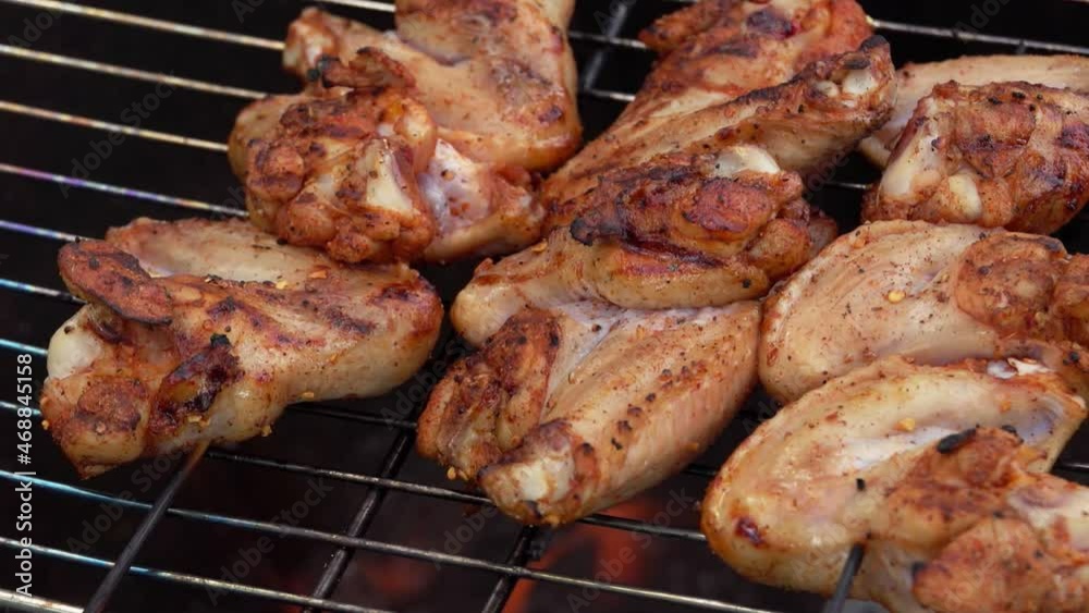 The appetizing chicken wings on the skewers are frying and roasting on the grill The appetizing chicken wings on the skewers are frying and roasting on the grill