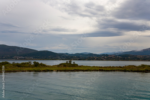 Stromy nature scenery landscape of the narow island in the sea surrounded by mountain and dramatic clouds on horizon background in the dawn