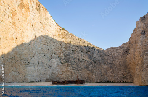 A sandy beach with a shipwreck surrounded by impenetrable clifs and turquoise waters of the Aegean Sea photo
