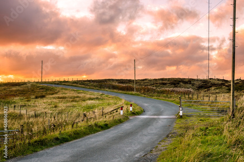 Dramatic colourful autumn sky over a narrow country road at sunset. Yorkshire, UK.