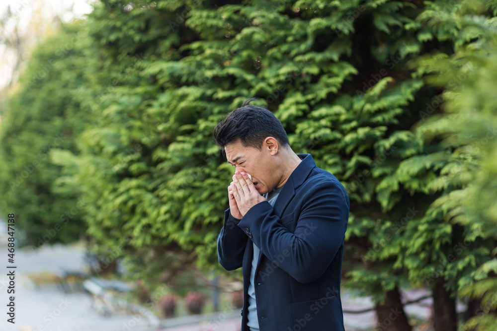 Businessman tired and sick asian man sneezes and coughs on the street, allergic reaction Businessman tired and sick asian man sneezes and coughs on the street, allergic reaction