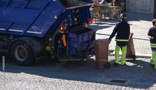 Camião de recolha de lixo com um homem a colocar contentores de lixo para serem despejados dentro do camião - limpar a cidade photo