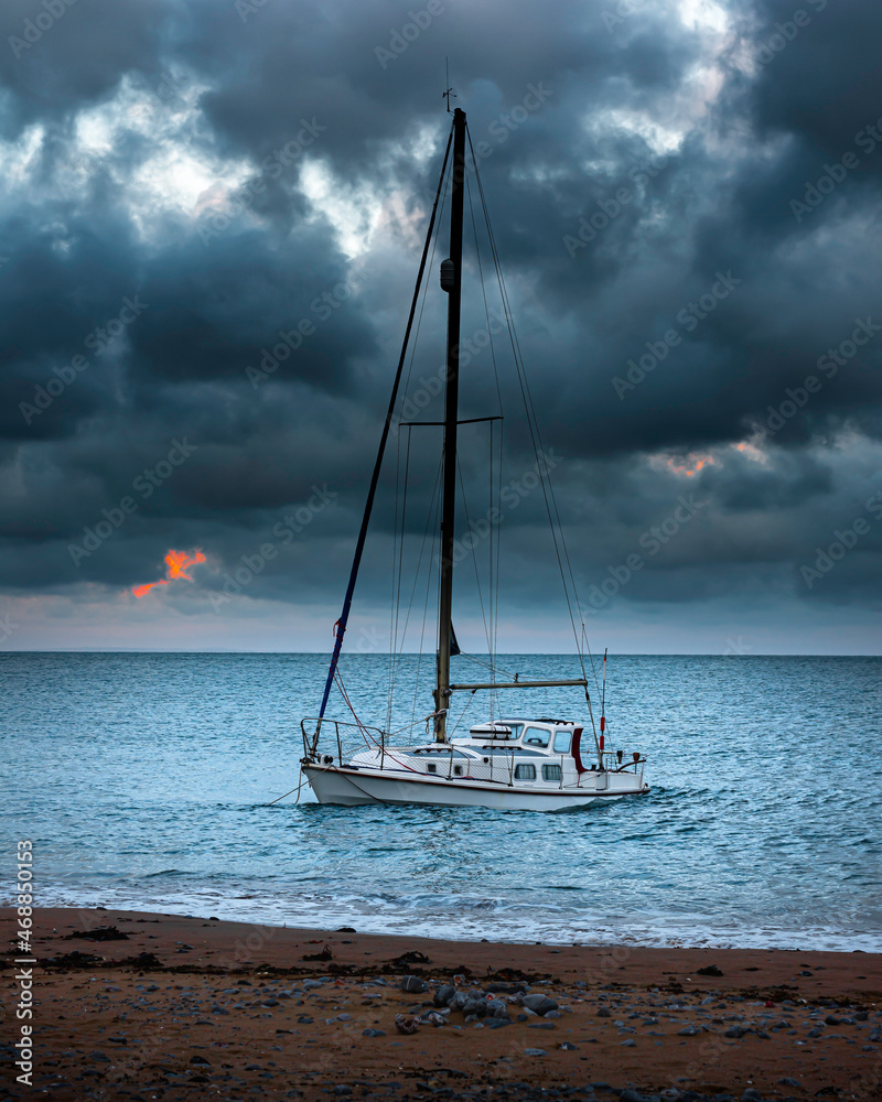 Dramatic sky with dark clouds over the sea with a boat moored near the beach.