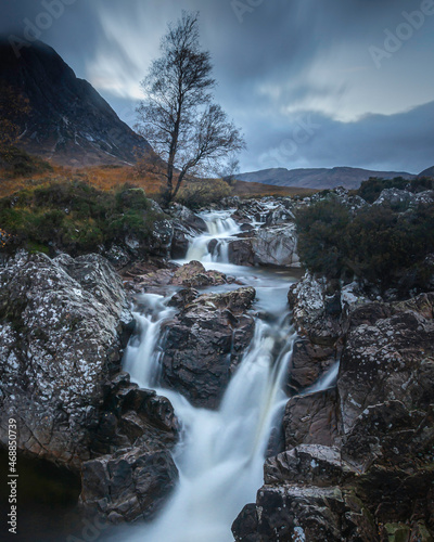 Waterfall and the lone tree in Glencoe, Scottish Highlands.Blue hour landscape scenery.