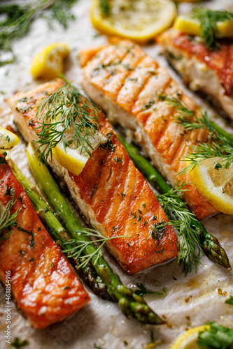 Картината върху платно Baked salmon fillets and green asparagus with aromatic herbs and lemon on baking