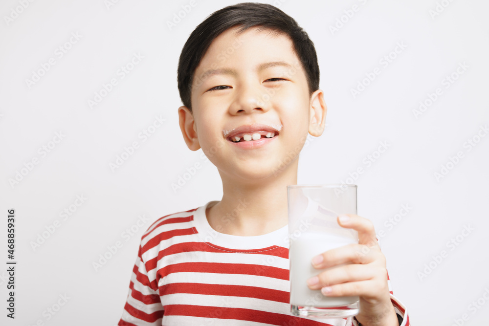 Happy and strong asian little boy hold a glass of milk and cheerful