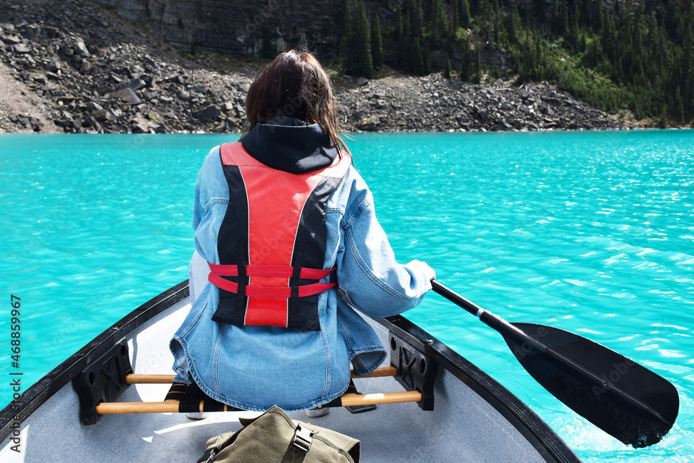 Young girl paddling in canoe on turquoise lake