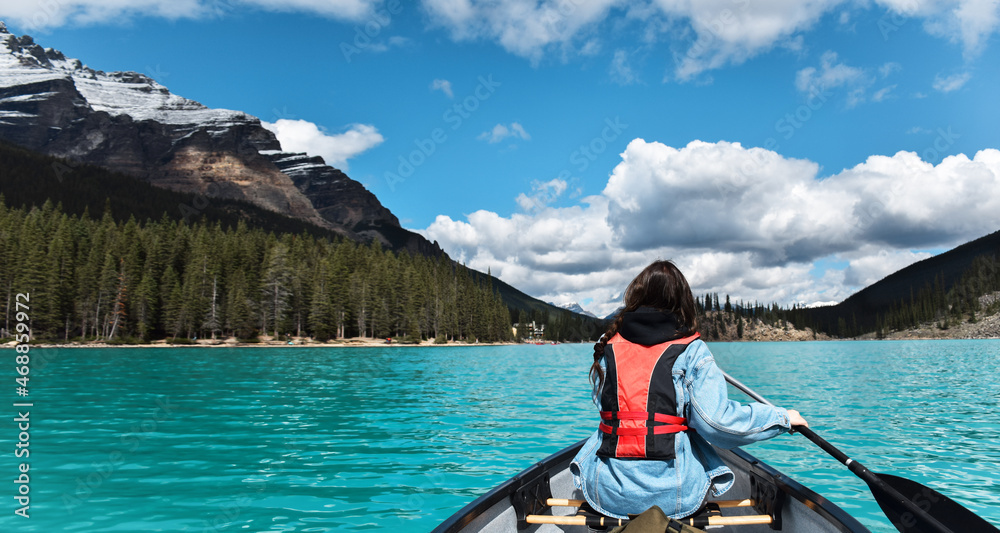 Young girl paddling in canoe on turquoise lake web banner