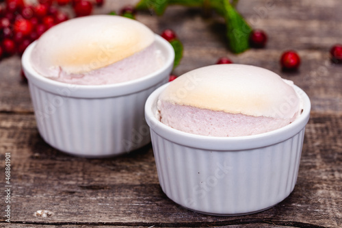 Souffle with cranberries in white ramekin on wooden rustic table. Close up