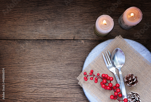 Autumn table setting with candles, berries, ceramic plates, spoon and fork on wood background. Thanksgiving