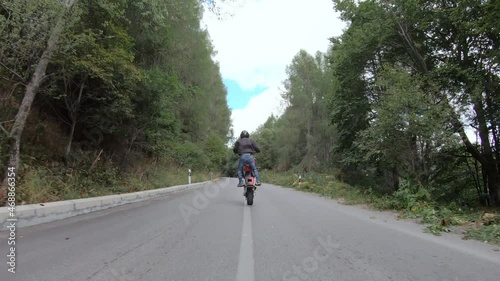 Fast motorcycle stunt road riding. having fun driving dangerous wheelie on mountain rural road photo