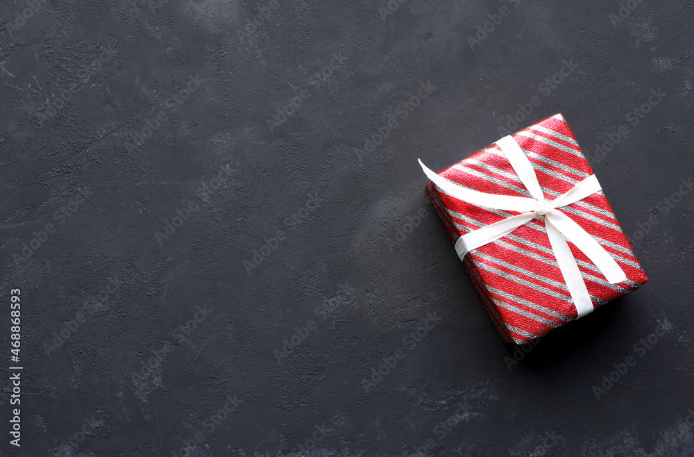 Red luxury gift box on black background. Christmastime celebration. Space for text.