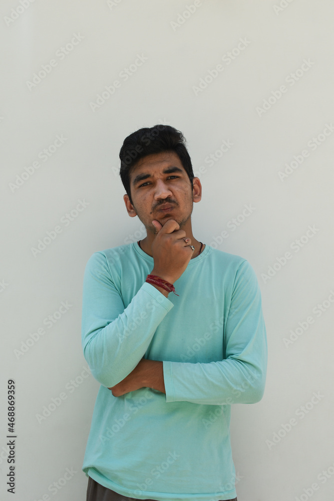 Man looking at camera thinking something and hand on chin wearing mint green t-shirt in isolated white background. Man looking at camera thinking something and hand on chin wearing mint green t-shirt in isolated white background.