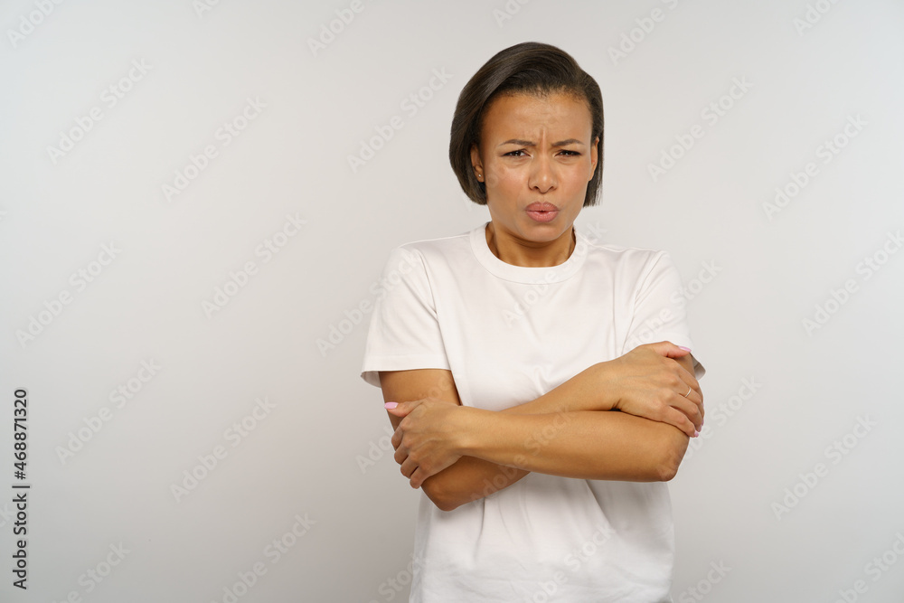 Unpleased african woman looking with disgust stand with folded hands dissatisfied frowning. Unhappy shocked black female with gross reaction and grimace emotions on face isolated over studio wall Unpleased african woman looking with disgust stand with folded hands dissatisfied frowning. Unhappy shocked black female with gross reaction and grimace emotions on face isolated over studio wall
