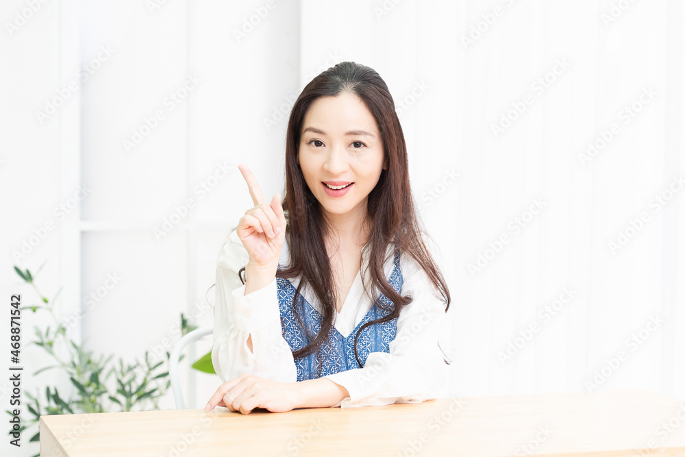 人差し指でポイントを示すリビングで座っている主婦 人差し指でポイントを示すリビングで座っている主婦