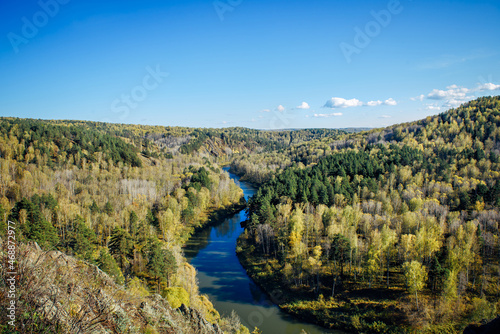 Beautiful view of wooded hills and river bends under clear blue sky. Peaceful natural landscape in a national park. Nature of Siberia.