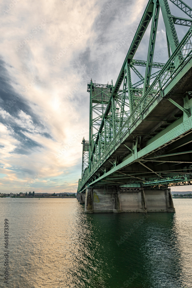 Truss lift sectional bridge over the Columbia River against a cloudy evening sky connects the states of Oregon and Washington