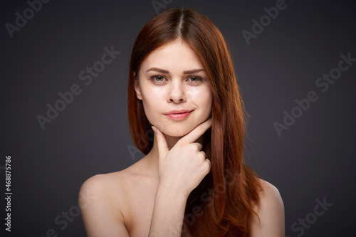 pretty red-haired woman naked shoulders posing dark background