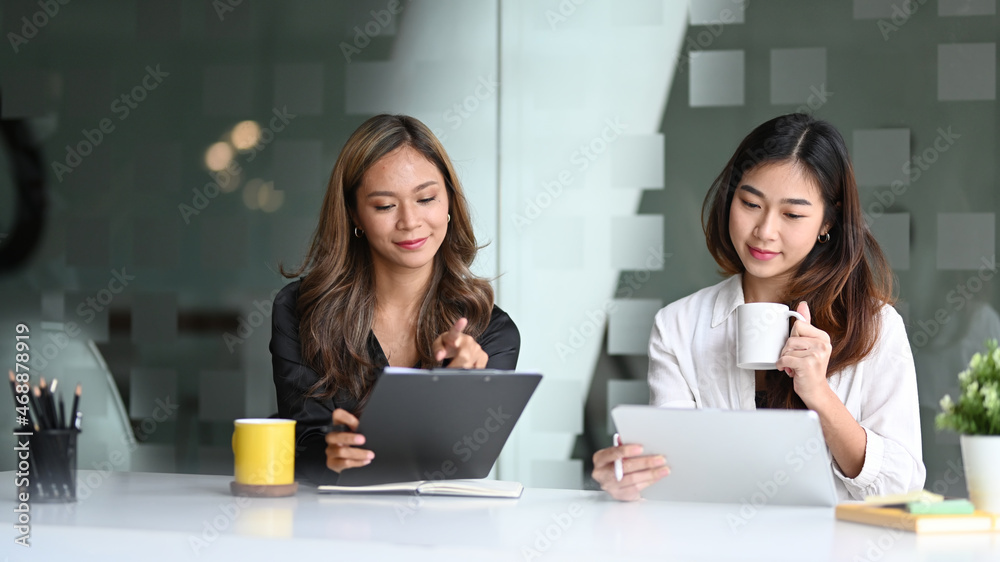 Two businesswomen sitting in office and sharing ideas or startup business plan together. Two businesswomen sitting in office and sharing ideas or startup business plan together.