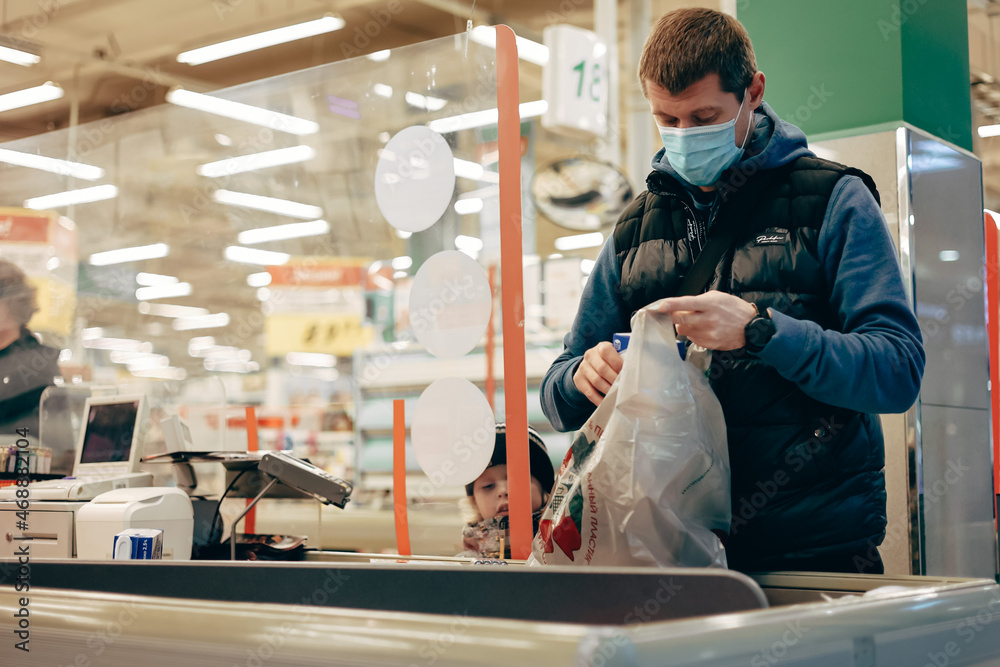 Man in protective medical mask buying food at grocery store or supermarket during quarantine, lockdown, coronavirus pandemic.