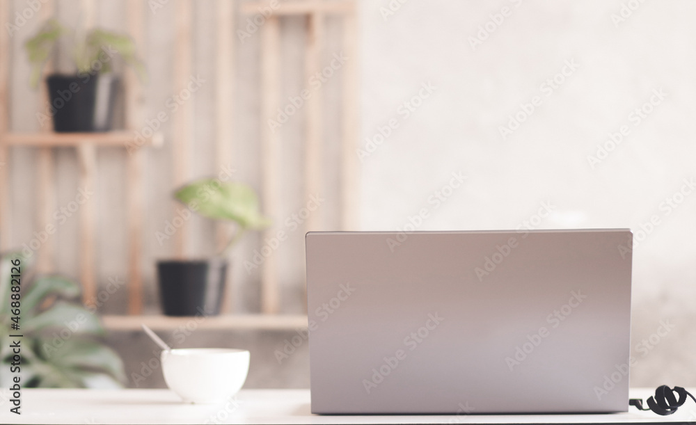 Close up view of comfortable office desk with laptop, mug, copy space on white table in glass partition office Close up view of comfortable office desk with laptop, mug, copy space on white table in glass partition office