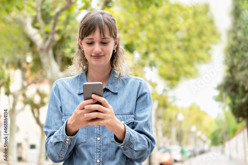 A woman using her phone with both hands outside