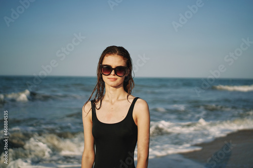 pretty woman in black swimsuit posing sun walking on the beach