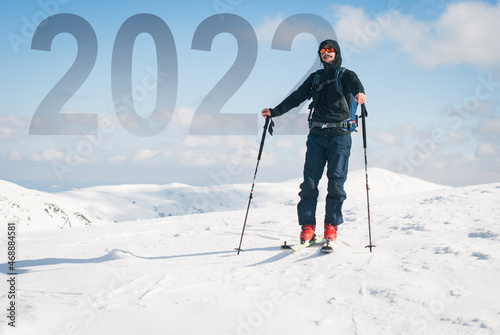 A happy young man who reached the new year 2022 summit. Backcountry skiing in the mountains.