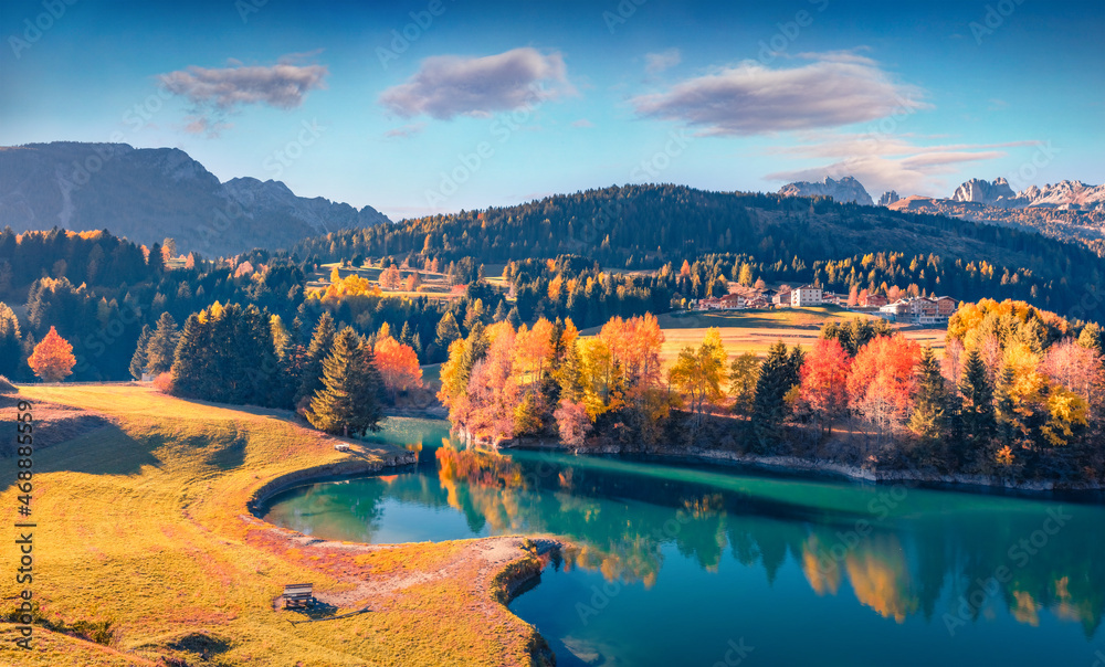 Aerial autumn view of Soraga lake. Wonderful morning cityscape of Soraga di Fassa village, Province of Trento, Italy, Europe. Spectacular outdoor scene of Dolomite Alps. Traveling concept background..
